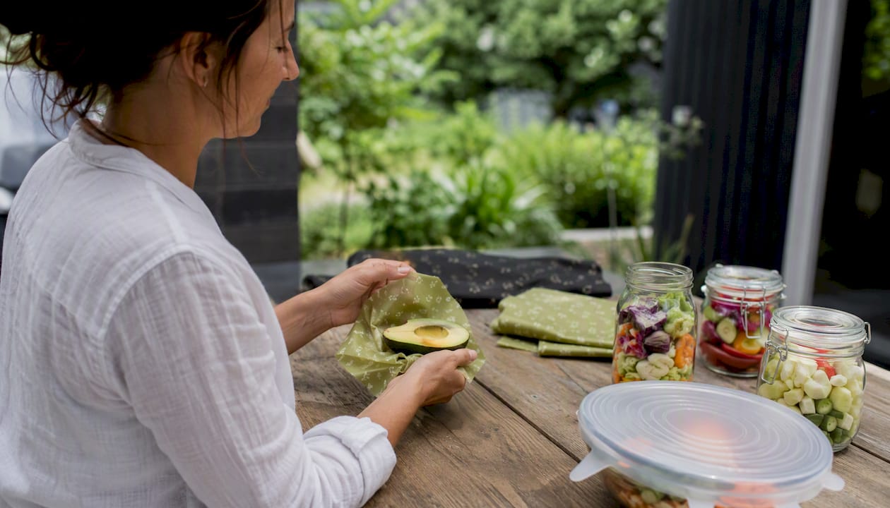 Hands wrapping avocado with beeswax wrap in eco kitchen