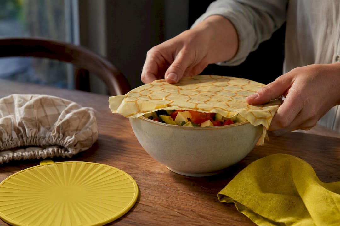 Hands pressing beeswax wrap over bowl